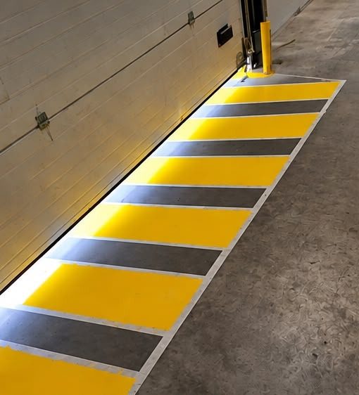 Nez de quai signalé en jaune et gris devant une porte sectionnelle